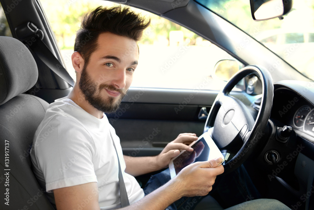 Portrait of young handsome driver with tablet computer