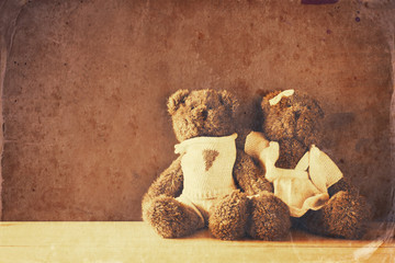 couple of cute teddy bears hugging on wooden table.