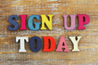 Sign up today written with colorful letters on rustic wooden surface

