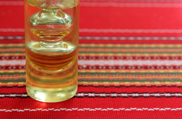 Olive oil in an unusual glass bottle on a background of red tabl