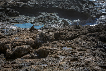 Wall Mural - Flat rocky shore with ocean foam of sea water. Scene lit with sunlight. Natural pattern wet stone textures.