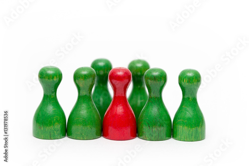 Fotografía rote Spielfigur aus Holz zwischen grünen Spielfiguren isoliert