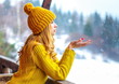 cute lovely girl in a knitted cap and sweater holding out palm of the hand under falling snow outside the city