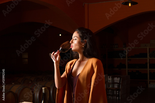 Fotografía Elegant young woman wine tasting in winery cellar.
