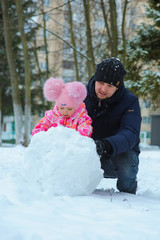 Little girl and her dad playing in the snow