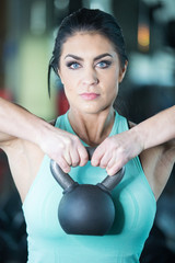 Wall Mural - Healthy woman with piercing blue eyes holding weight ball in gym