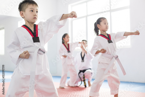 Fotografía Young instructor teaching children taekwondo in studio