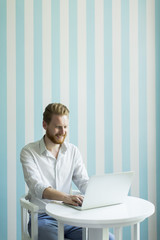 Wall Mural - Young redhair man working on laptop in room