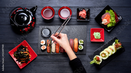 Cuadros en Lienzo Woman eating sushi with chopsticks top view
