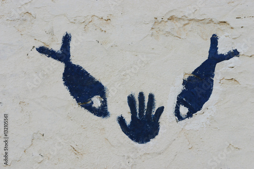 Fotografia Hand and fish symbol on the wall in the sahara Tunisia