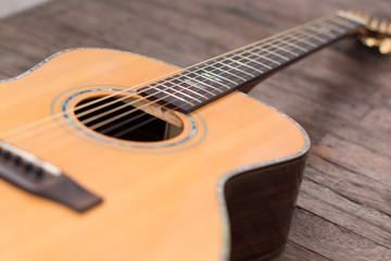 Acoustic guitar resting against a wooden background with copy sp