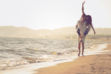 A guy carrying a girl on his back, at the beach, outdoors