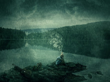 Young Boy, Artist With A Guitar And Books, Sit Down On A Rocky Shore Near The Lake And Forest. Bad Mood, Hard Thinking, No Inspiration Concept With His Head Fired And The Smoke Rising Up.