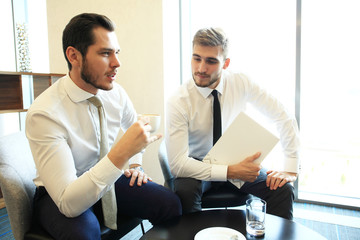 Canvas Print - Image of two young businessmen using touchpad at meeting.