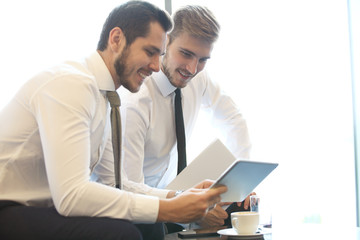 image of two young businessmen using touchpad at meeting.