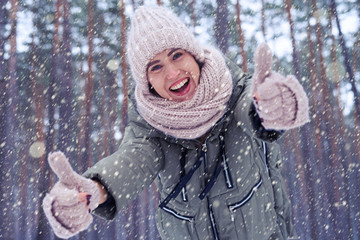 Wall Mural - Merry young model outdoors in the winter forest holding thumb up