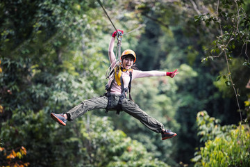 Woman Tourist Wearing Casual Clothing On Zip Line Or Canopy Experience In Laos Rainforest, Asia