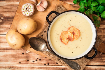 Wall Mural - Homemade potato cream soup with potato chips on wooden table