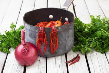 Fresh steamed crayfish. Two crayfish hanging on the tails. Boiled crawfish with parsley and spices. Rustic style. Wooden background.