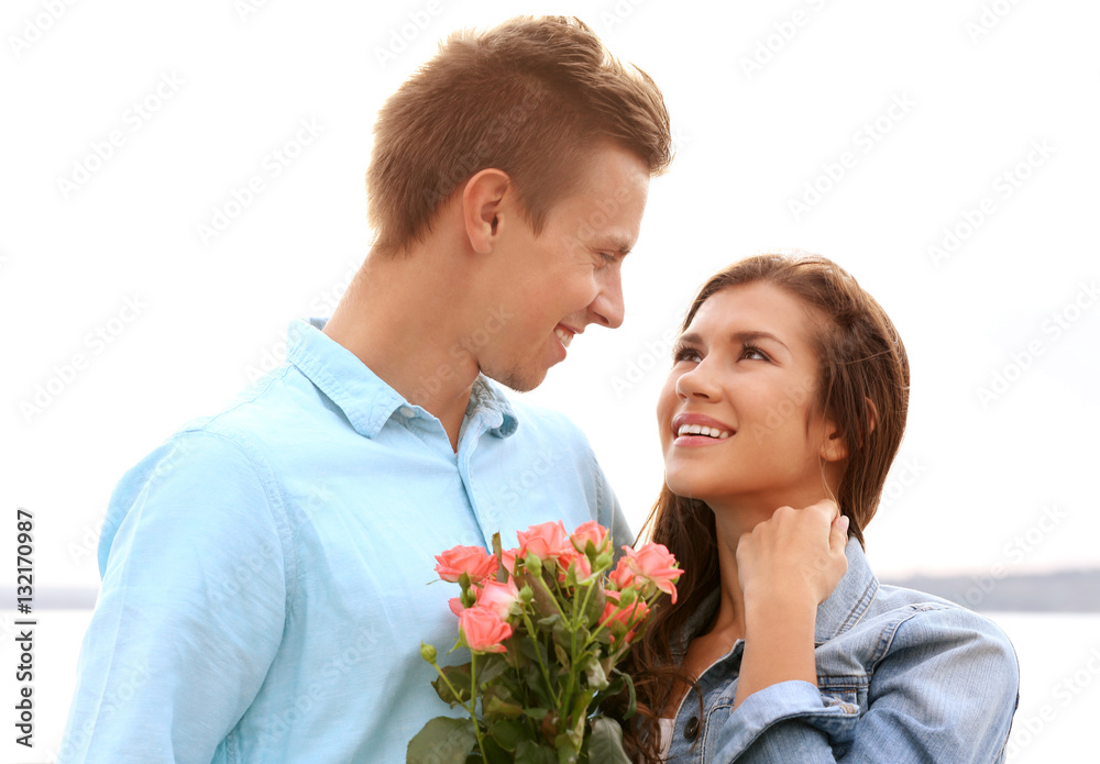 Beautiful young couple near river on light background