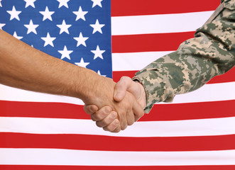 Wall Mural - Soldier and civilian shaking hands with USA flag on background. Civilians protection concept