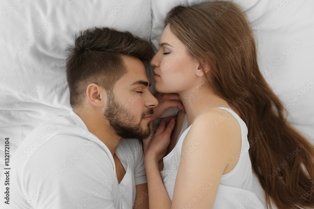 Cute young couple lying in bed at home