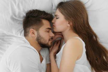 Wall Mural - Cute young couple lying in bed at home