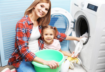 Wall Mural - Pretty woman and her daughter doing laundry at home