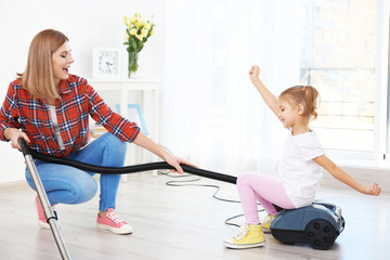 Wall Mural - Little girl and her mother playing while doing cleanup at home