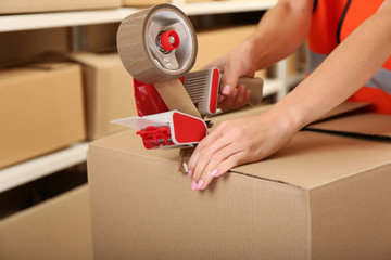 female hands packing box at warehouse, closeup