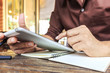 © memorystockphoto - businessman writing notes from ipad mini at coffee shop. selective focus, over light