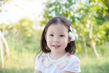 Wall Mural - Little asian girl with flower on hair in garden