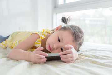 Wall Mural - Little asian girl playing game on cellphone