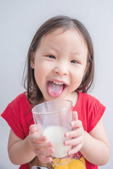 Wall Mural - Little asian girl smiles after drinking milk from glass