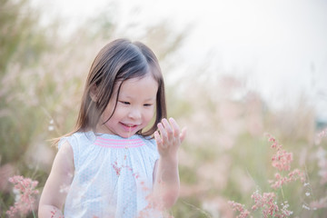 Wall Mural - Little asian girl playing with wild flower in field