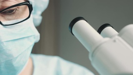 Wall Mural - middle age female scientist in uniform and medical face mask doing microscopic examination in labora