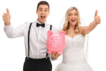 Wall Mural - Overjoyed newlyweds holding a piggybank and giving thumbs up