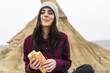 © Westend61 - Spain, Navarra, Bardenas Reales, portrait of smiling young woman eating baguette in nature park