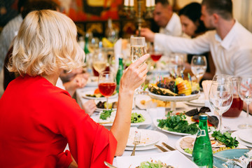 hand of stylish woman holding glass of champagne and toasting at luxury restaurant