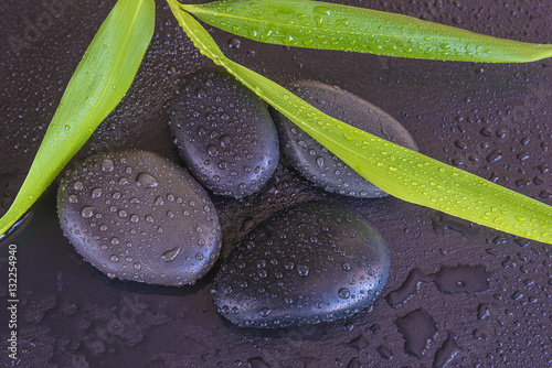 Obraz w ramie spa concept/massage stones and bamboo leaves with water drops on wet slate background top view