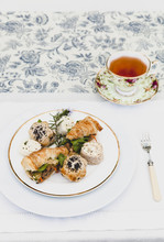 Tea Cup On Place Setting  And Finger Sandwiches On Tablecloth