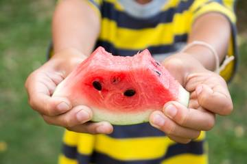 Wall Mural - Close up of happy boy is holding watermelon on green nature back