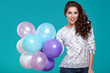 © ZoomTeam - Happy young woman standing over blue wall and holding balloons.