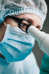 Wall Mural - close up view of scientist eye in glasses looking at microscope.