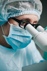 Wall Mural - close up view of scientist eye in glasses looking at microscope.
