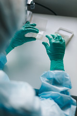 Wall Mural - close up crop view of scientist hands putting microscope glasses in special store box.