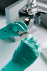 Wall Mural - close up crop view of scientist hands putting microscope glasses in special store box.