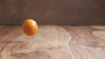 Wall Mural - clementines falling on wood table in slow motion, 180fps prores footage