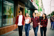 © dashamuller - Four happy trendy teenage friends walking in the city, talking each other and smiling. Lifestyle, friendship and urban life concepts.