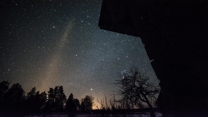 Wall Mural - Timelapse of stars over timber house at winter night then clouds coming on dark sky.